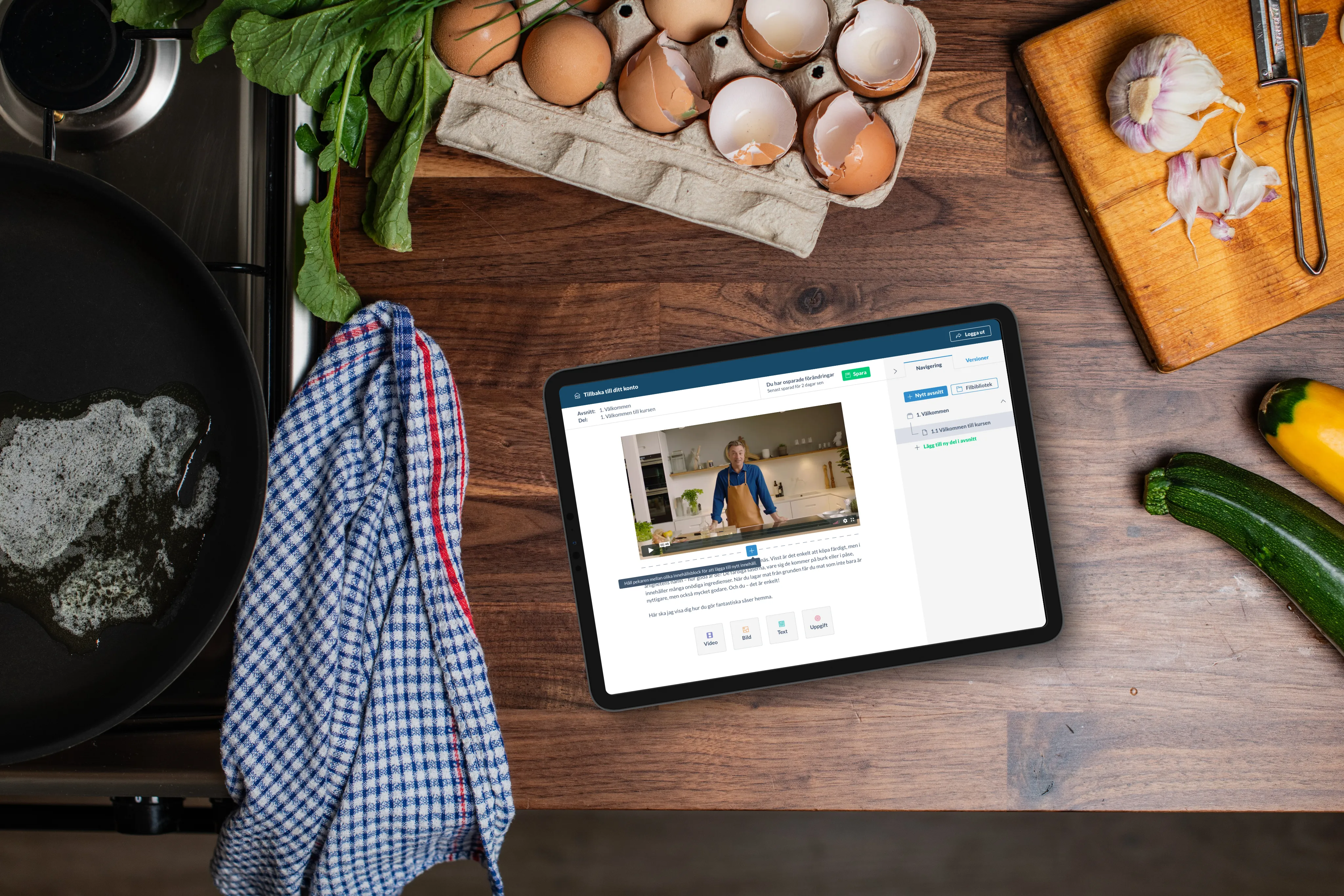 A tablet showing the Brillbee course tool on a wooden table next to a kitchen towel